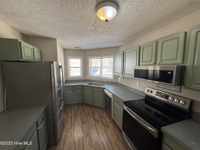 kitchen with appliances with stainless steel finishes, a sink, and green cabinetry