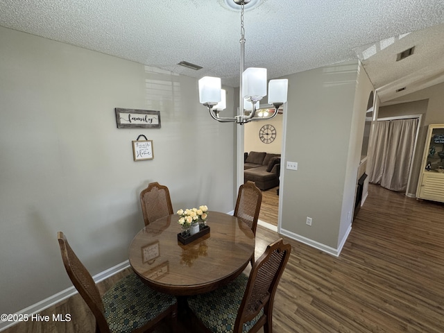 dining room with visible vents, an inviting chandelier, a textured ceiling, wood finished floors, and baseboards