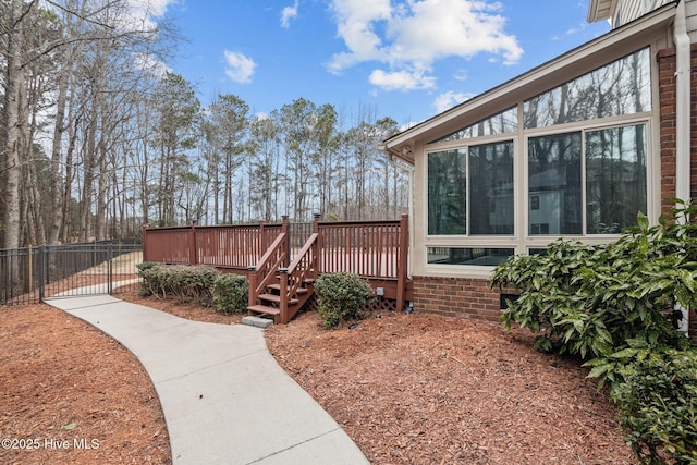 view of yard featuring a sunroom, fence, and a deck