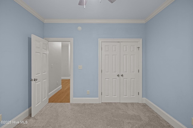 unfurnished bedroom featuring a closet, ornamental molding, a ceiling fan, carpet flooring, and baseboards