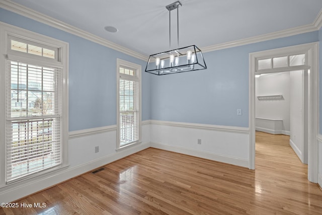 unfurnished dining area with light wood-type flooring, visible vents, ornamental molding, and a chandelier