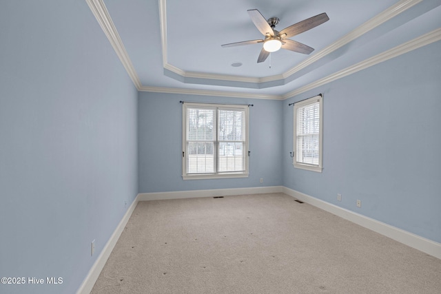 carpeted spare room featuring ornamental molding, a tray ceiling, and baseboards