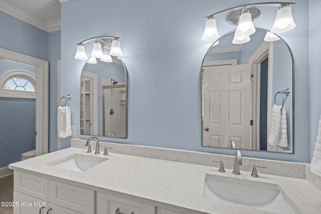 bathroom with ornamental molding, a stall shower, a sink, and toilet