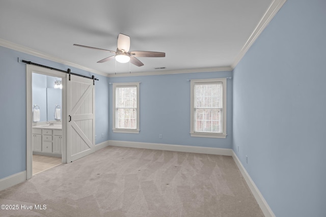 unfurnished bedroom with light carpet, crown molding, baseboards, and a barn door