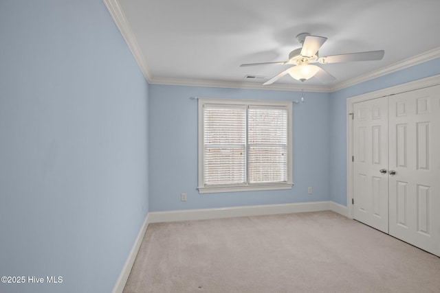 unfurnished bedroom with crown molding, a closet, light colored carpet, ceiling fan, and baseboards