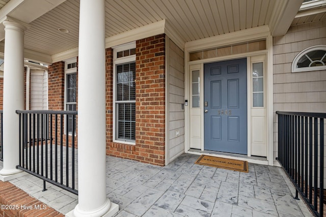 property entrance with covered porch and brick siding