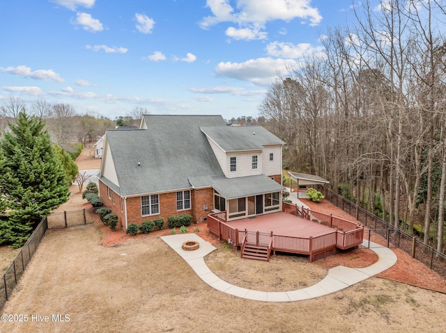 rear view of house featuring a fire pit, brick siding, a fenced backyard, and a wooden deck