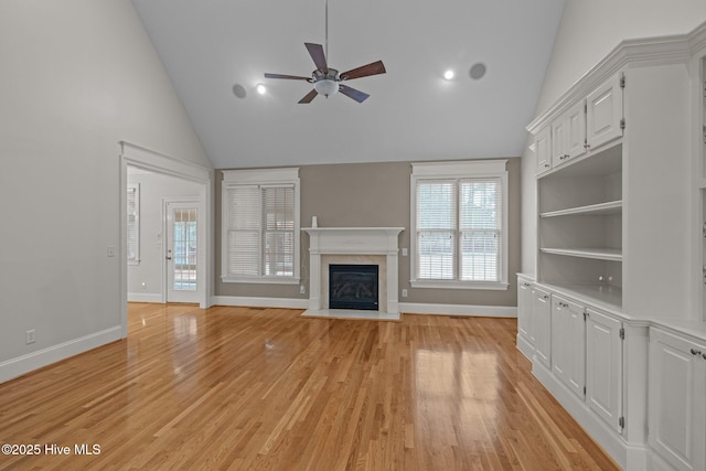 unfurnished living room with a fireplace with flush hearth, baseboards, ceiling fan, and light wood finished floors