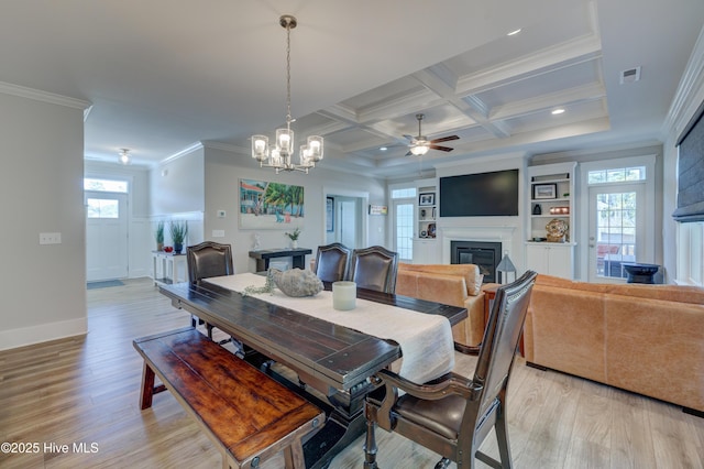 dining area featuring ornamental molding, a glass covered fireplace, a healthy amount of sunlight, and coffered ceiling