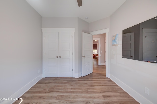 unfurnished bedroom featuring a closet, light wood-type flooring, a ceiling fan, and baseboards