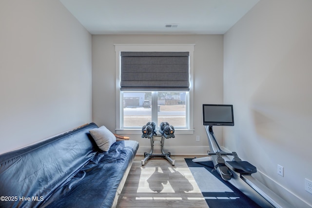 exercise area with wood finished floors, visible vents, and baseboards