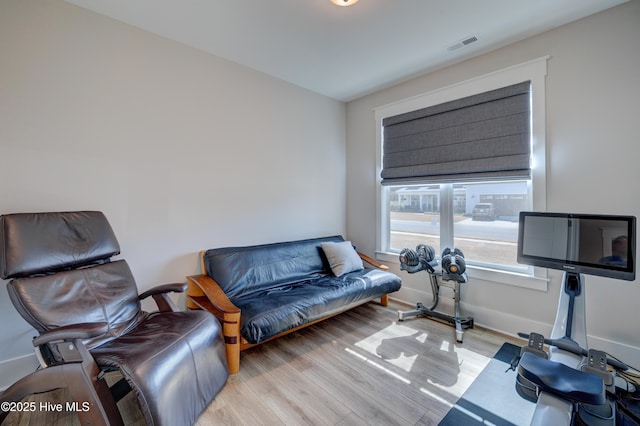 living room with light wood finished floors, baseboards, and visible vents