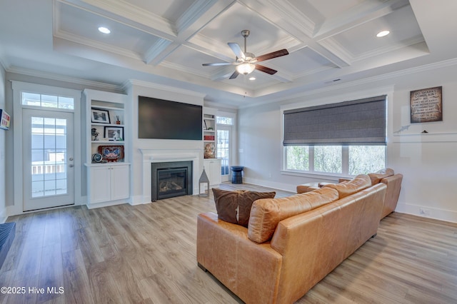 living room with light wood-style flooring, coffered ceiling, and a glass covered fireplace