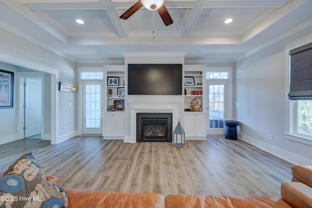 unfurnished living room with light wood finished floors, coffered ceiling, and a glass covered fireplace