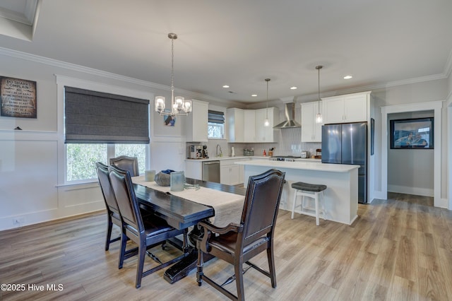 dining room with light wood-style floors, plenty of natural light, an inviting chandelier, and crown molding