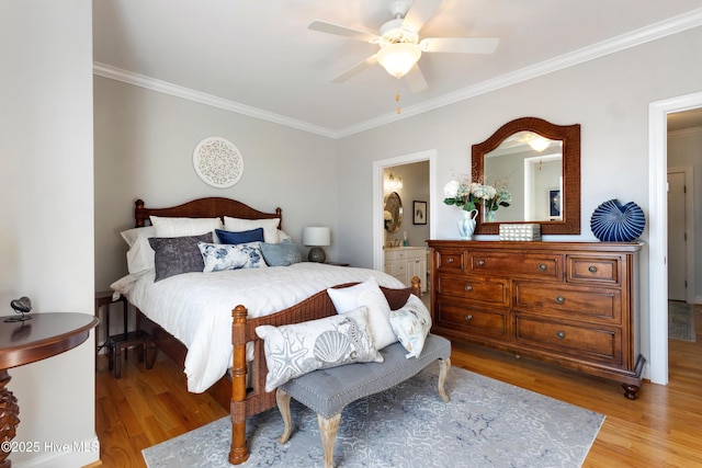 bedroom with light wood-style floors, ensuite bath, and ornamental molding