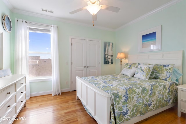 bedroom with ornamental molding, light wood-type flooring, a closet, and visible vents