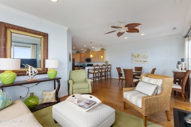 living room with crown molding, recessed lighting, a ceiling fan, and light wood-style floors