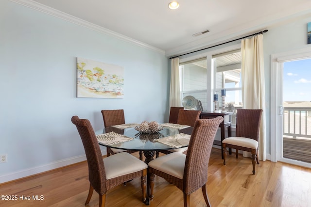 dining area with light wood-style flooring, visible vents, ornamental molding, and baseboards