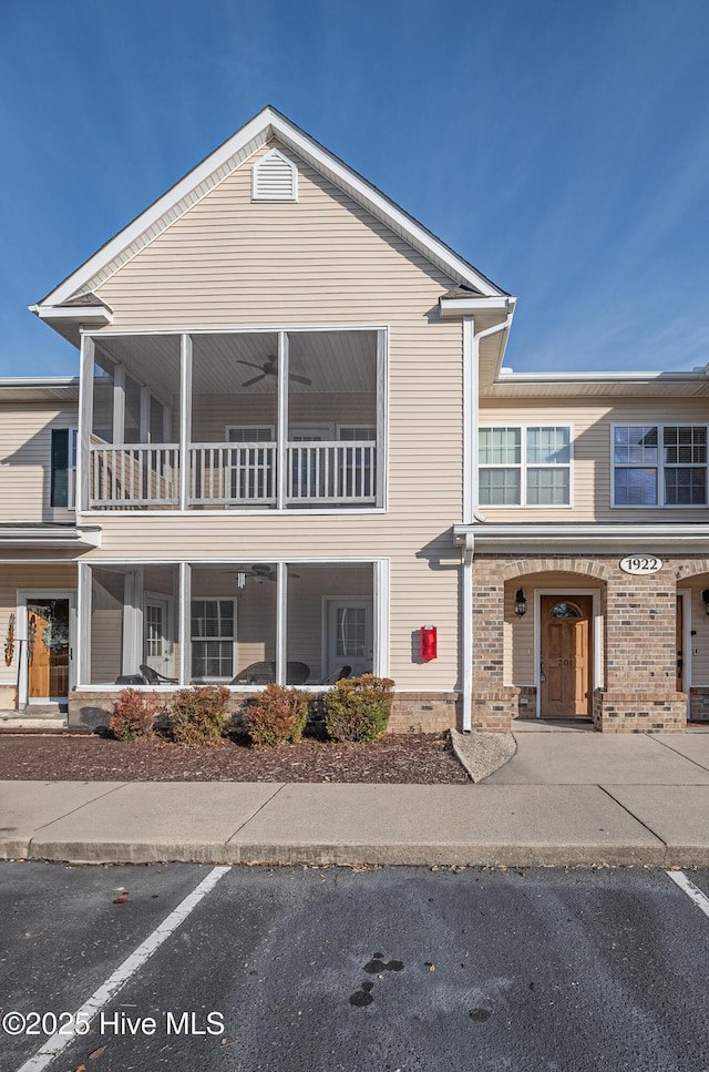 view of property with ceiling fan, uncovered parking, and brick siding