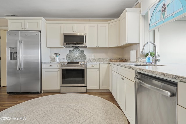 kitchen featuring light stone counters, dark wood-type flooring, a sink, visible vents, and appliances with stainless steel finishes