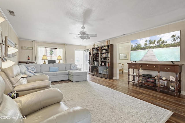 living room with visible vents, ornamental molding, a ceiling fan, wood finished floors, and baseboards