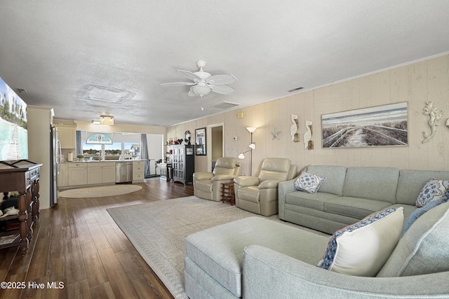 living room with crown molding, dark wood-style flooring, visible vents, and ceiling fan