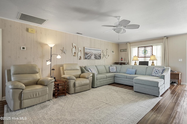 living room with a ceiling fan, visible vents, crown molding, and wood finished floors