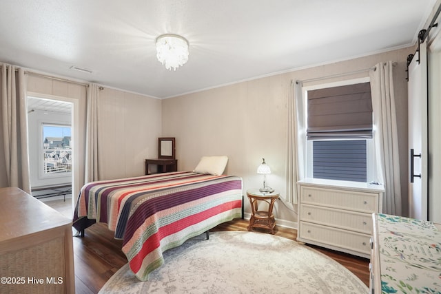 bedroom featuring a barn door, wood finished floors, and crown molding