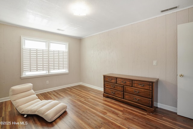 sitting room with ornamental molding, visible vents, baseboards, and wood finished floors