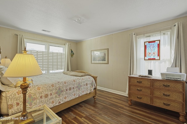 bedroom featuring visible vents, dark wood-type flooring, ornamental molding, a textured ceiling, and baseboards