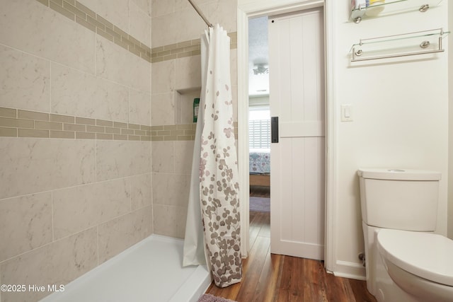 bathroom featuring baseboards, a shower stall, toilet, and wood finished floors