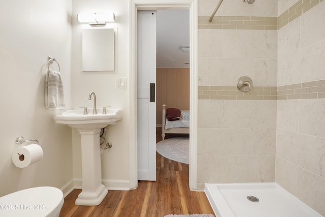 bathroom featuring toilet, a stall shower, baseboards, and wood finished floors