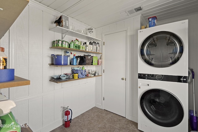 clothes washing area with laundry area, visible vents, and stacked washer / drying machine