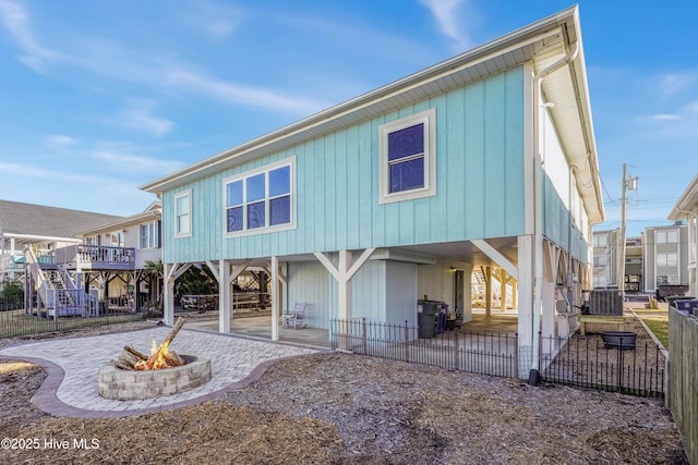 rear view of property featuring a patio area, an outdoor fire pit, fence, and a carport