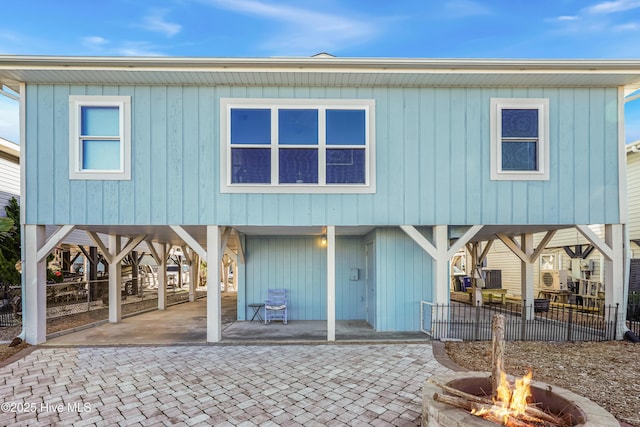 back of property with a carport, an outdoor fire pit, decorative driveway, and a patio area