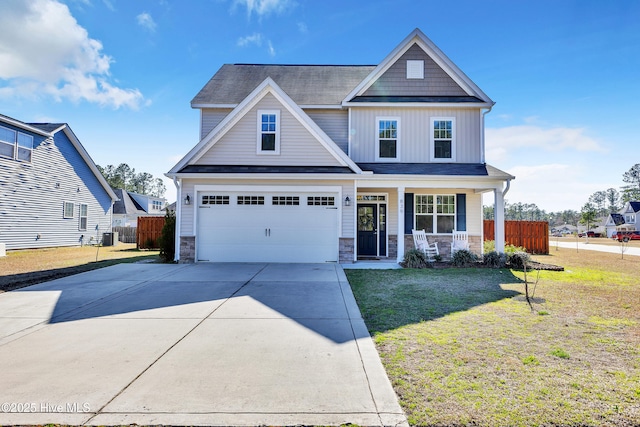 craftsman house with fence, a porch, concrete driveway, stone siding, and board and batten siding