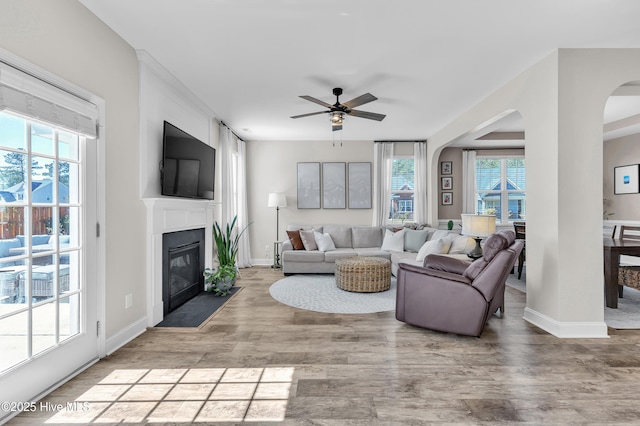 living room with a fireplace with flush hearth, baseboards, and wood finished floors