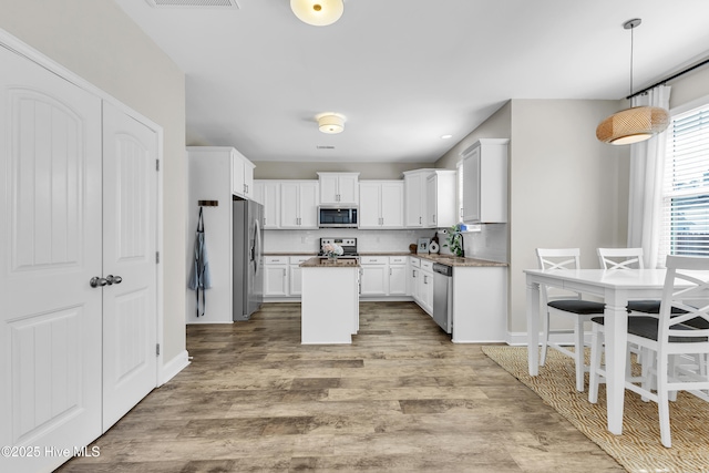 kitchen featuring decorative backsplash, appliances with stainless steel finishes, light wood-style floors, white cabinetry, and a sink