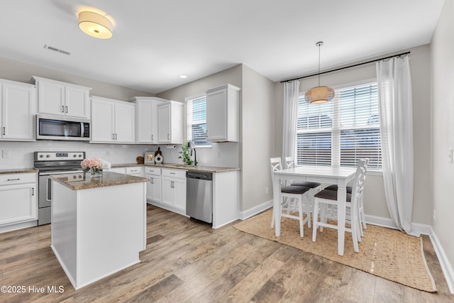 kitchen with visible vents, light wood-style flooring, a sink, appliances with stainless steel finishes, and decorative backsplash