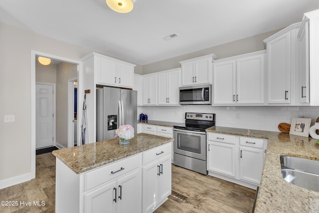 kitchen featuring visible vents, light wood finished floors, appliances with stainless steel finishes, backsplash, and a center island