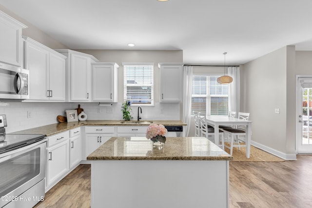 kitchen featuring light wood finished floors, white cabinets, appliances with stainless steel finishes, and a sink