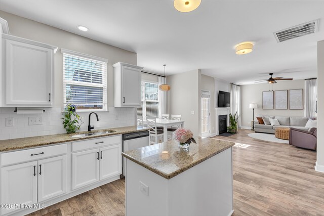 kitchen featuring visible vents, a sink, white cabinets, light wood-style floors, and backsplash