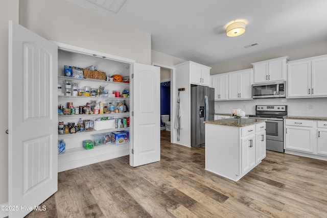 kitchen featuring backsplash, wood finished floors, appliances with stainless steel finishes, and a kitchen island