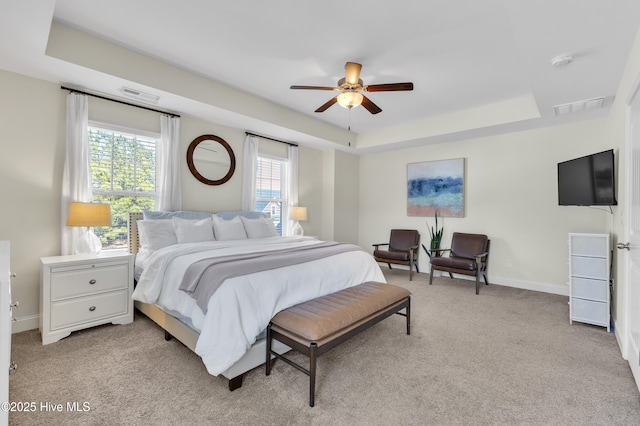 bedroom with visible vents, light colored carpet, baseboards, and a tray ceiling