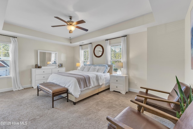 bedroom with light colored carpet, baseboards, and a tray ceiling