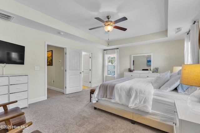 carpeted bedroom with visible vents, a raised ceiling, and baseboards