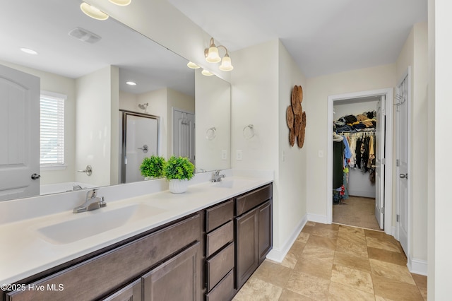 bathroom with a sink, baseboards, double vanity, and a shower stall