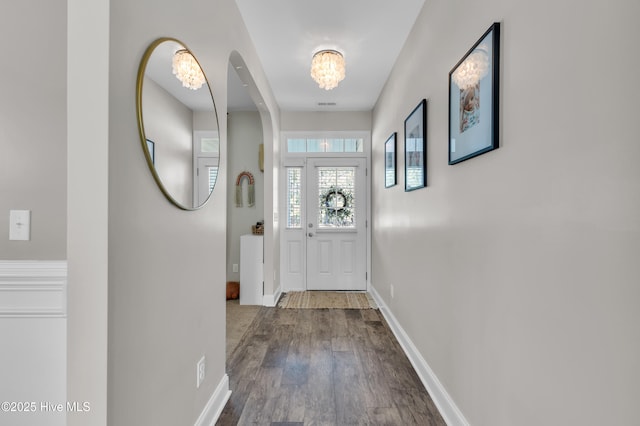 entryway with an inviting chandelier, wood finished floors, baseboards, and visible vents