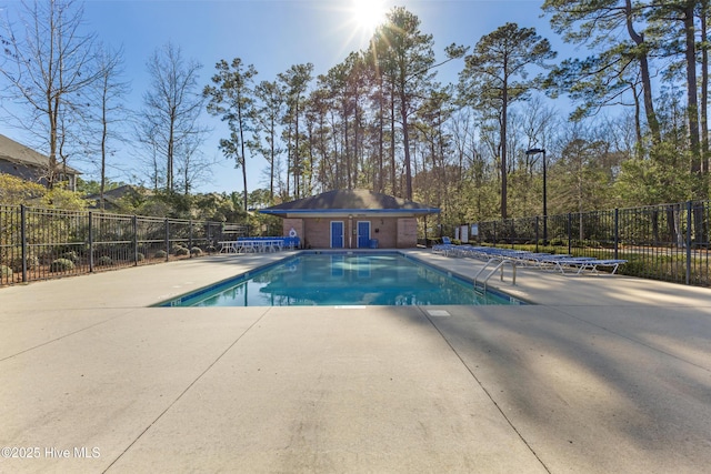 pool with fence, an outdoor structure, and a patio area